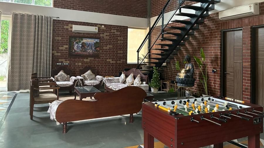 A well-lit living room with a modern interior, featuring a foosball table, comfortable seating, and a staircase leading to an upper level.