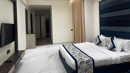 Modern bedroom with a flat-screen TV and stylish headboard - Lords Swastik Studio, Kodinar