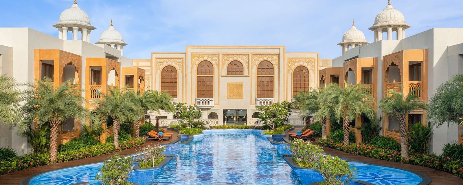 An image of a swimming pool surrounded by small trees and a building behind it - Accord Hotels and Resorts