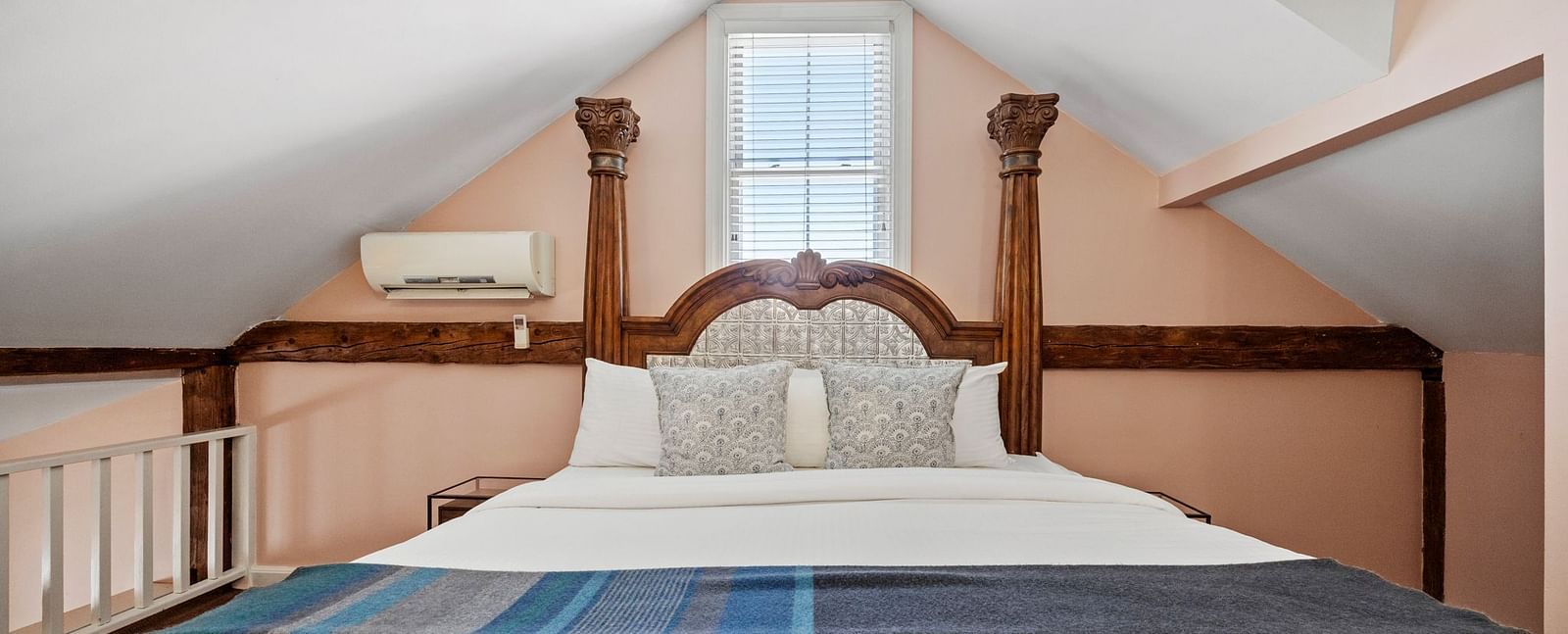A bedroom with sloped ceiling, skylights, and carved wooden bed at Hartstone Inn.