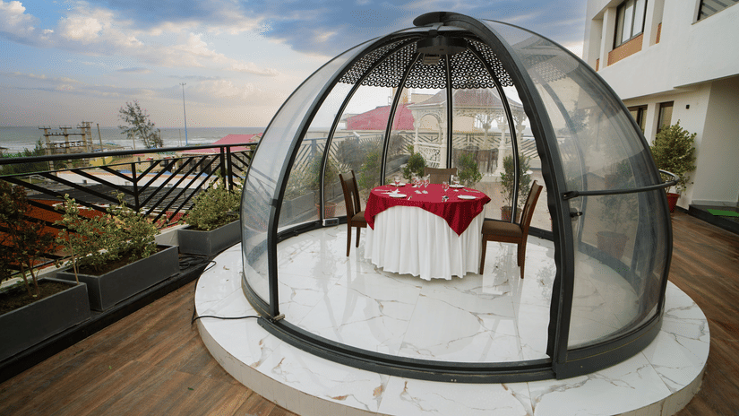A private glass dome dining setup at Shanti Seaview Resort & Spa featuring a romantic table arrangement on a rooftop deck with scenic sea views.