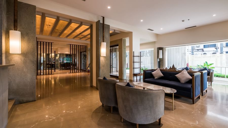 A stylish hotel lobby featuring comfortable grey sofas and warm lighting, perfect for relaxation at Shilton Dee Cee.