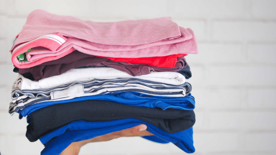 A hand holding a pile of neatly folded clothes
