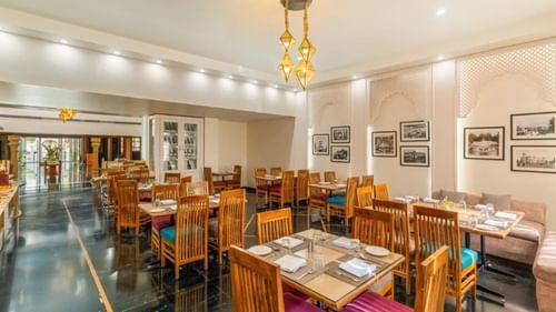 Indoor dining area with wooden furniture at Golden Tulip, Udaipur.