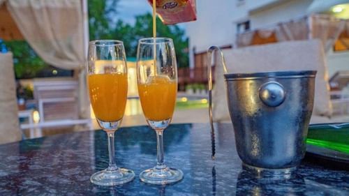 Close-up of orange drinks and ice bucket on a table near the pool at Golden Tulip, Udaipur.