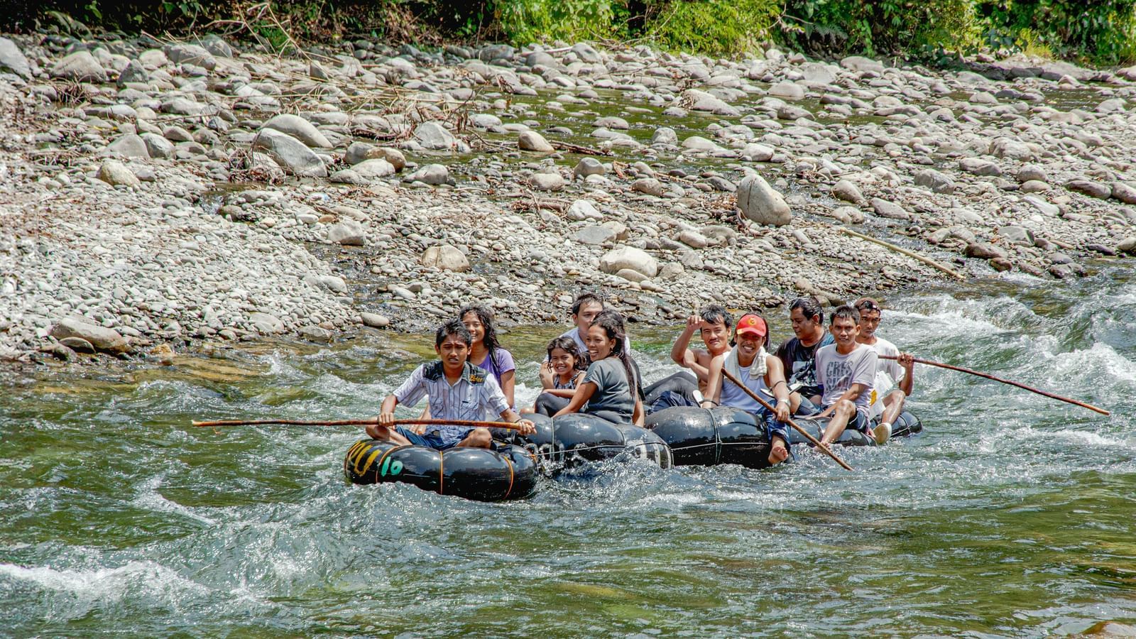 A group of people rafting together through flowing river water.