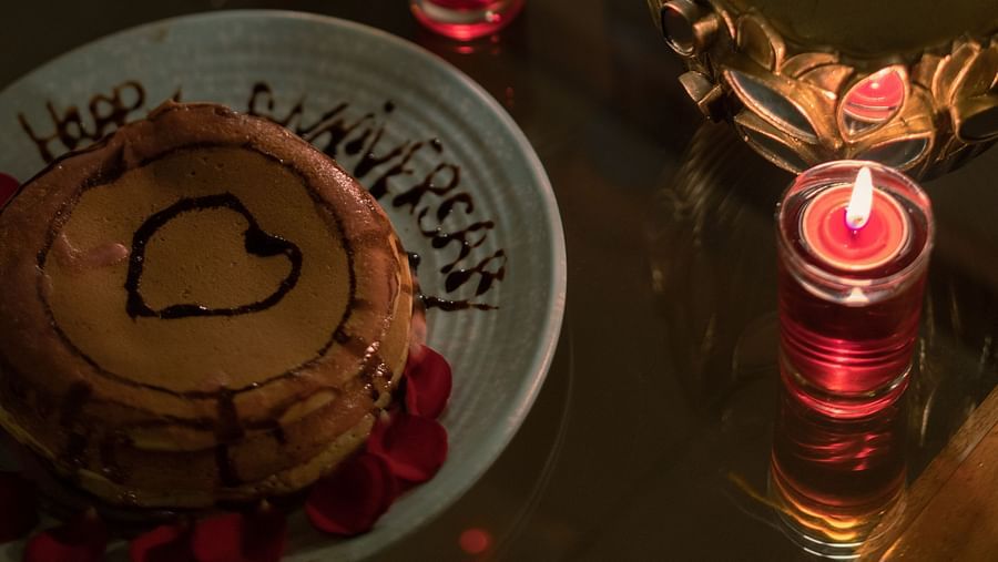 A close-up view of a glass table with a cake and candles placed around for decoration at BluSalzz Villas - The Green Roof, Bhimtal.