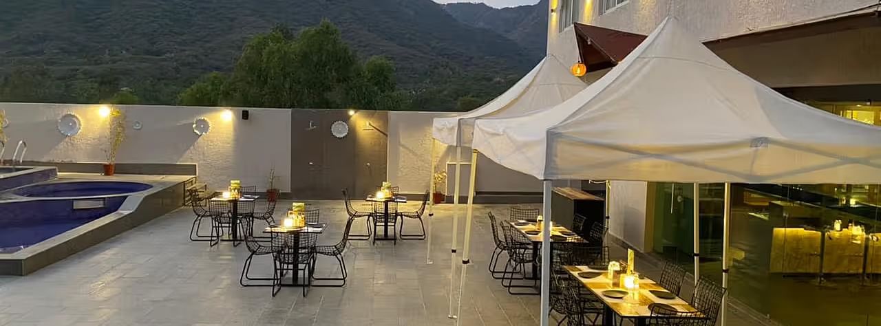 Tents, outdoor tables, building with a  mountain backdrop.