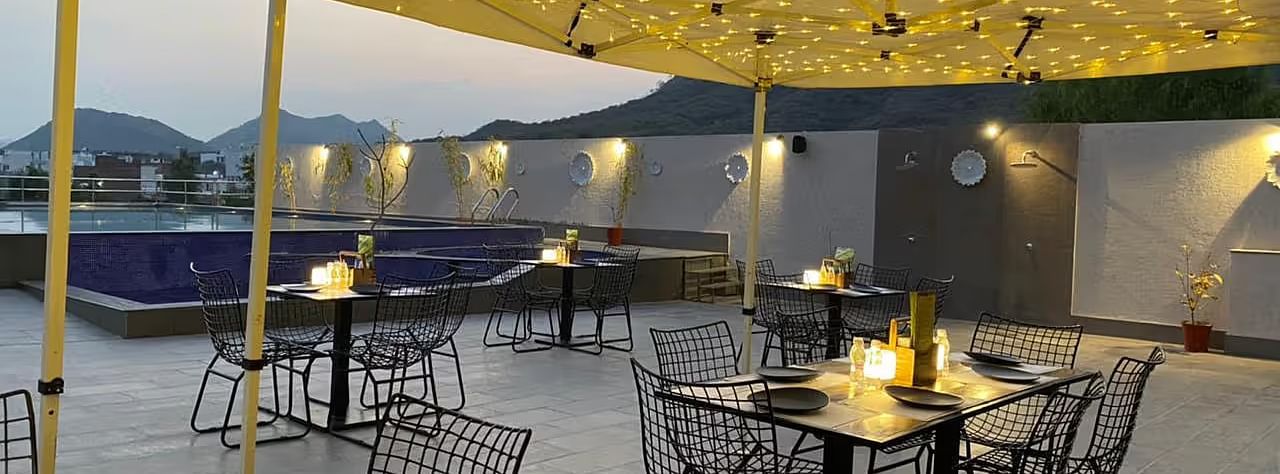 Outdoor patio with string lights, tables, and chairs, evening.