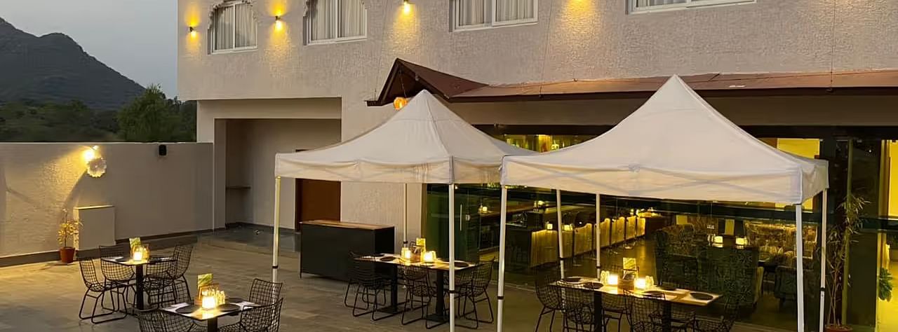 Building with tents, outdoor tables, warm lighting, dusk.