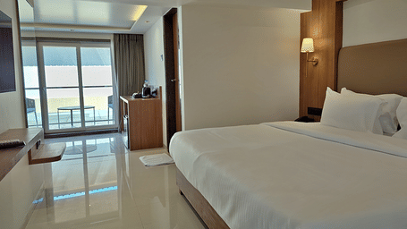 Bedroom with a double bed, wooden furnishings, bedside lights, and balcony access.
