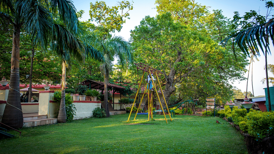 A wide angle view of the hotel garden with trees, swings and slides.
