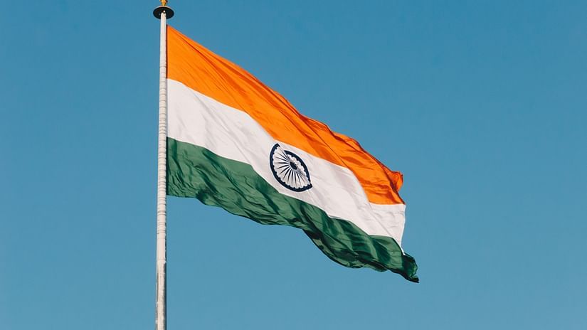 A far out view of the Indian Flag high on a pole with wind fluttering the flag