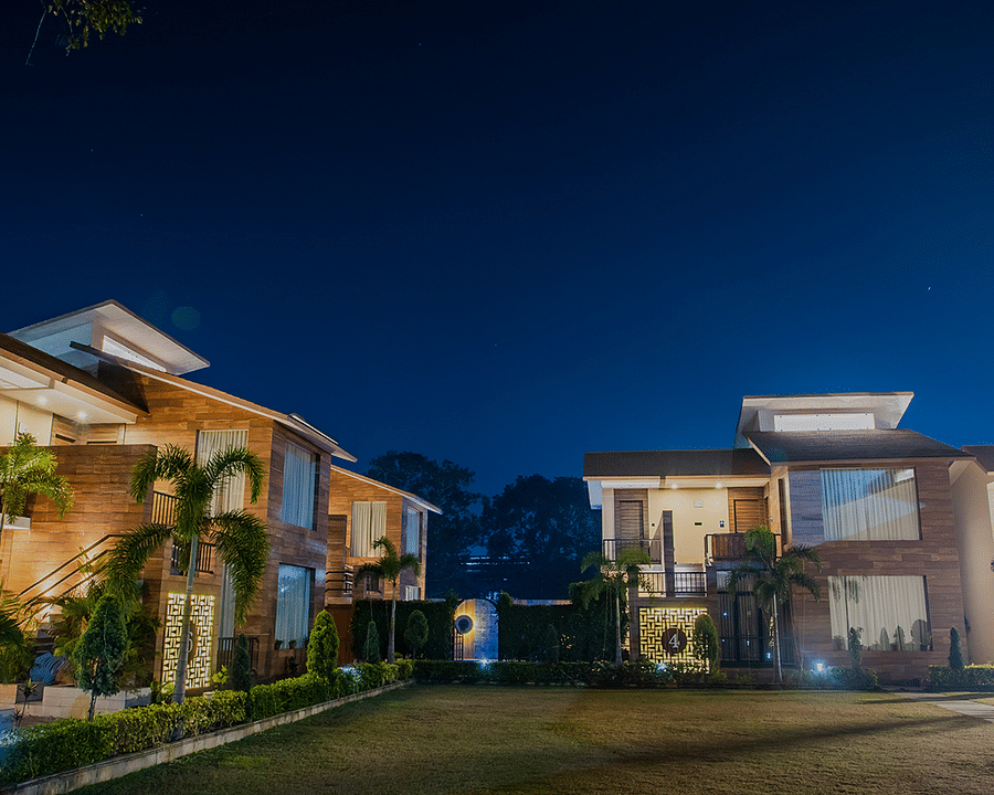 alt-text Night View of a Luxurious Resort with Illuminated Buildings and Lush Green Lawn