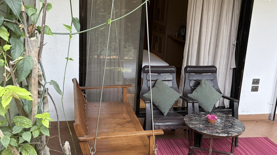 A wooden swing, 2 chairs, and a table at Bougainvillea, Alibaug.