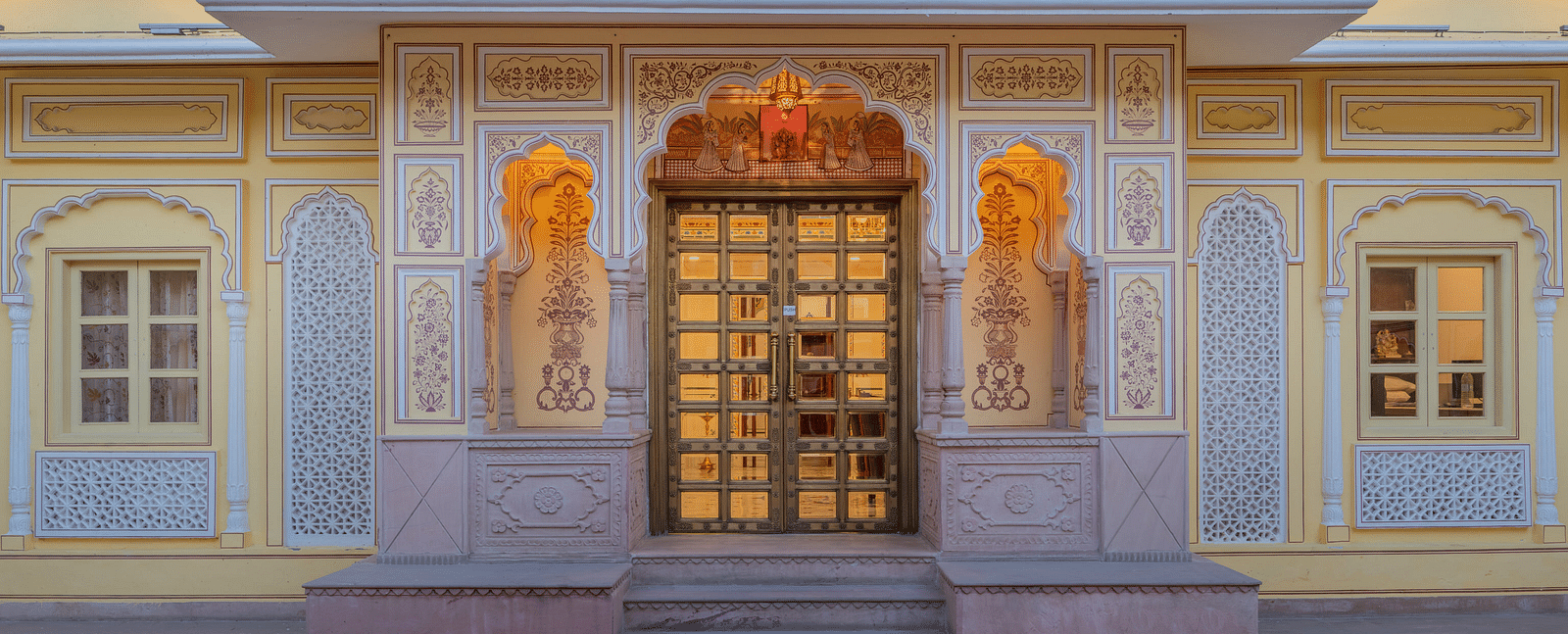 a close up stop of the entrance door with beautiful floral patterns painted on the wall - Brij Castle, Jaipur