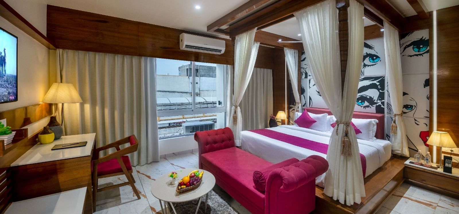 A room with a spacious bed, a small table with chairs, and a window with curtains at Angel Lords Eco Inn Amreli.