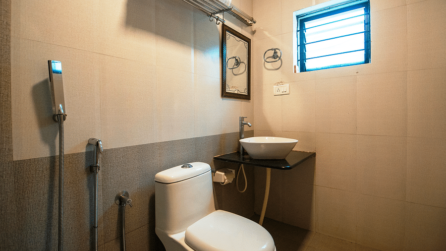 Image of a washroom with a toilet and a sink on the side at Coorg Jungle Camp Backwater Resort, Kushalnagar.