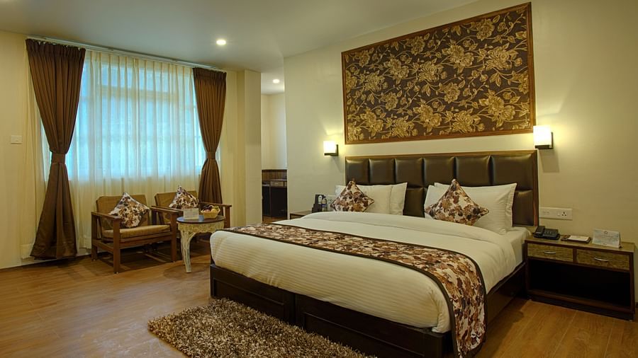 a cosy king size bedroom with with lavish interior and large windows covered with white windows - the aryan regency