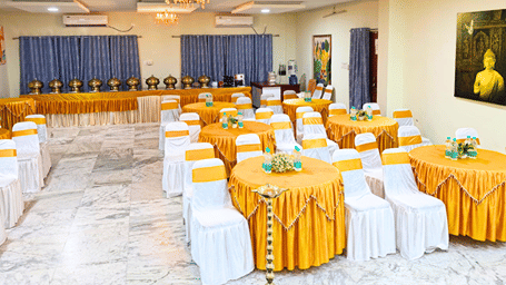 Shophori Wellness Retreat banquet hall in Santiniketan arranged with round tables and gold table settings for a large gathering