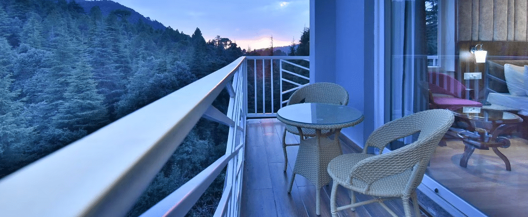 The balcony of the luxury room with two chairs and a coffee table overlooking the view - DLS Ark Holiday Inn, Dalhousie