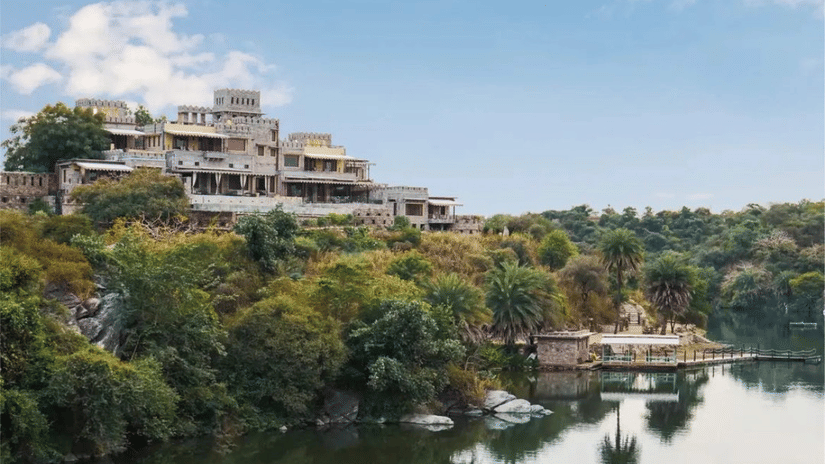 Facade of Chunda Shikar Oudi, Udaipur that is covered by forest area and the river in front of it