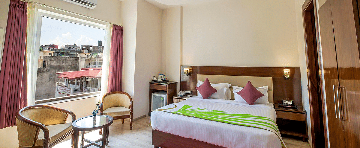 Full view shot of the Deluxe room featuring a double bed along with beautiful city views from the window at Regenta Inn DLS.
