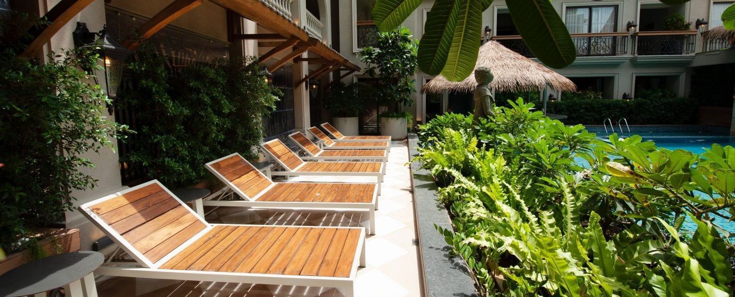 Side view of several sun loungers kept outside overlooking the green plants in front of it at The Evren, Vagator. 