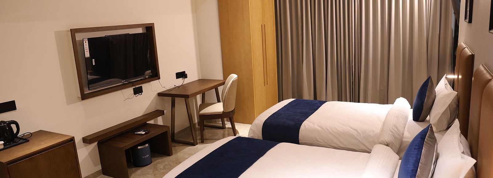 A spacious hotel room at Lords Eco inn Jamnagar Maheshwari Nagar with a large bed television and seating area.
