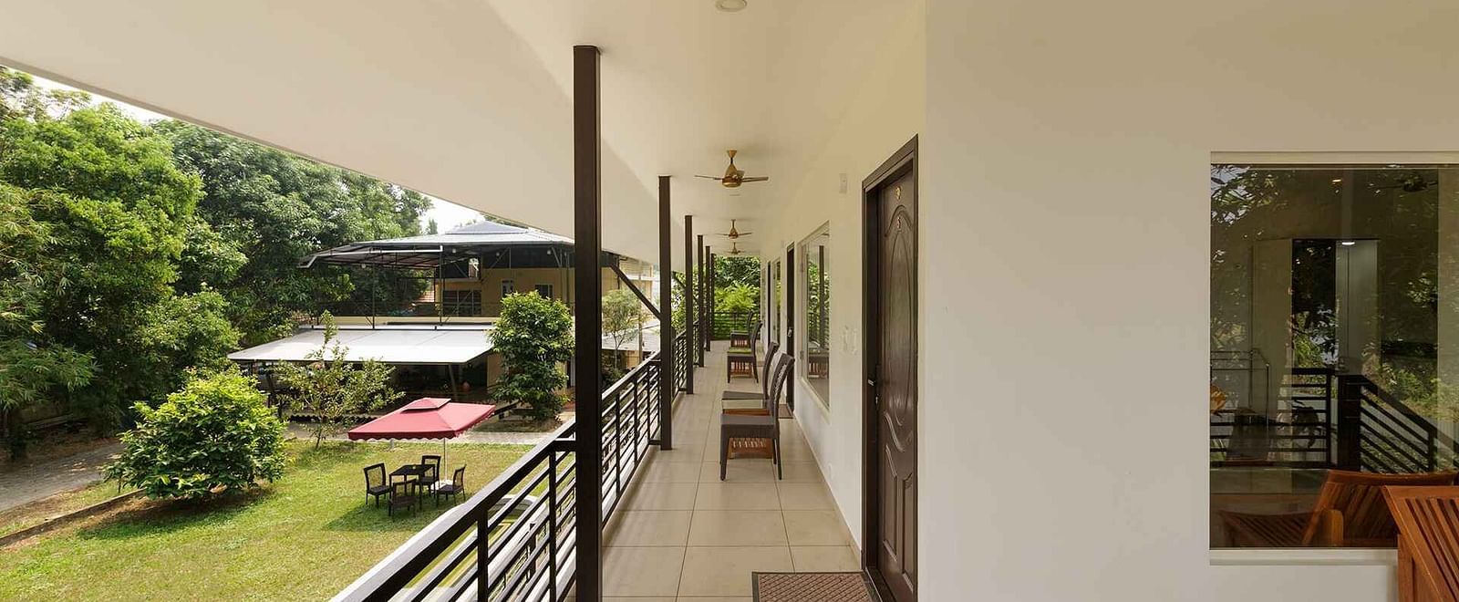 A long balcony or walkway with a view of lush greenery and possibly a body of water in the distance.