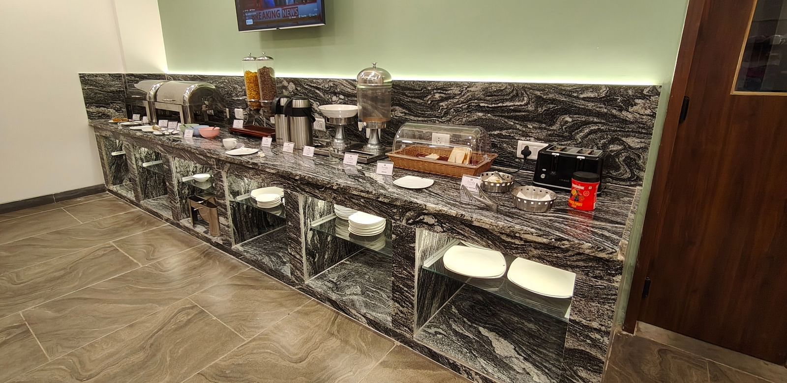 Buffet counter setup with various serving dishes and a mounted TV
