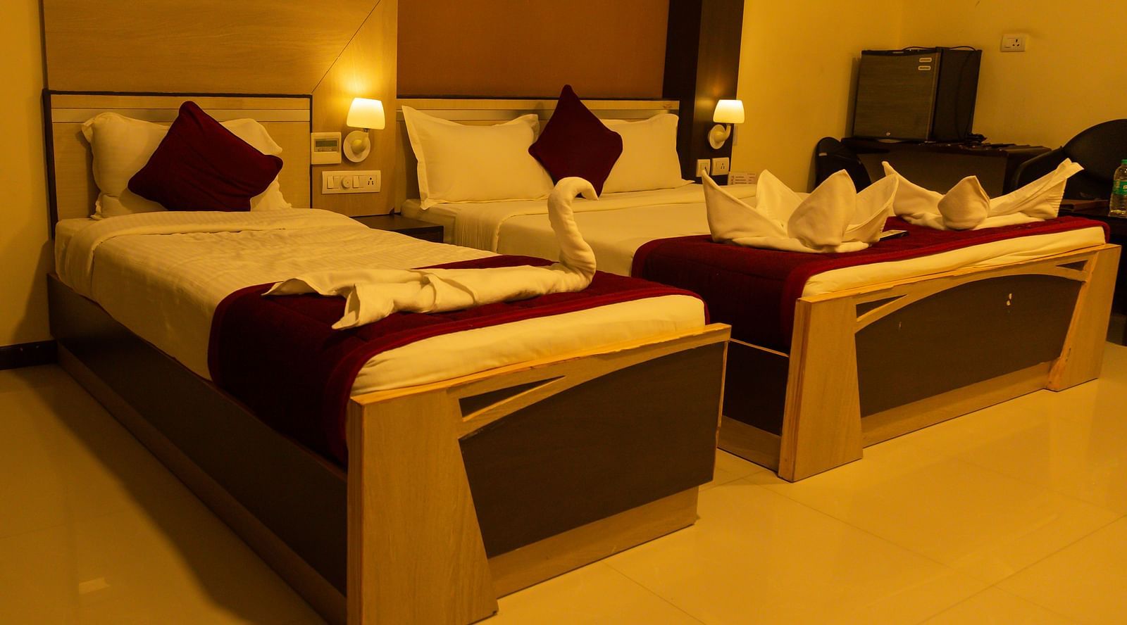 a bedroom with a large bed and a single bed with side drawers and a workdesk - Hotel Rockfort View, Trichy