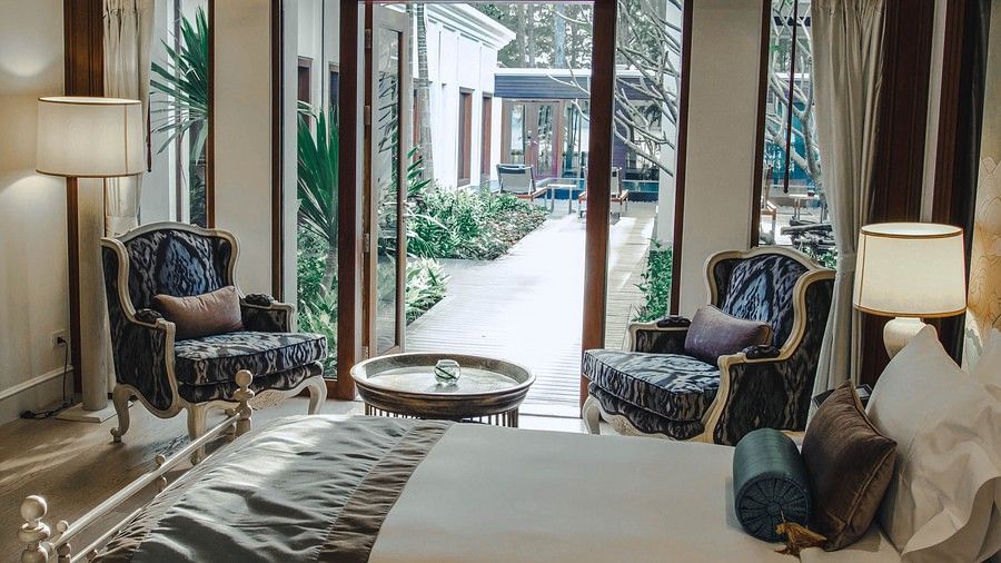 image of a bedroom with a twin bedroom and an armchair - two bedroom private pool beachfront villa
