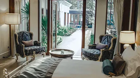 A luxurious bedroom with elegant armchairs and a view of a private outdoor area. - Maikhao Dream Villa Resort & Spa, Phuket