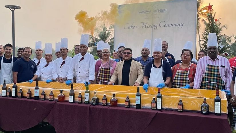 A group of prestigious people and chefs posing  behind a cabinet of liquor bottled in a cake mixing ceremony - Cloud9 Sarovar Premiere, Palolem Goa