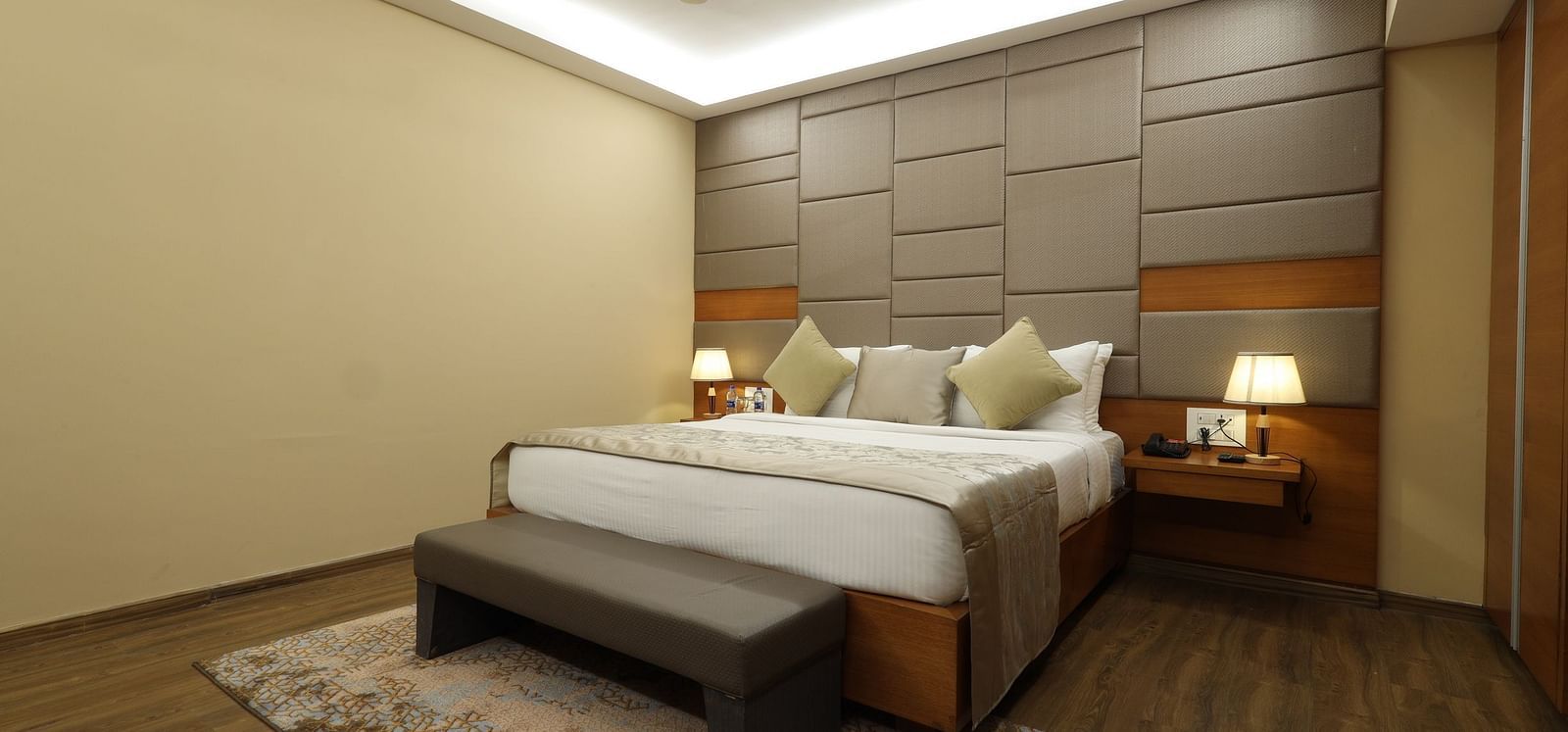 Hotel room interior with a bed, a bench, and a fan, a guest accommodation at Rang Lords Inn Bharuch
