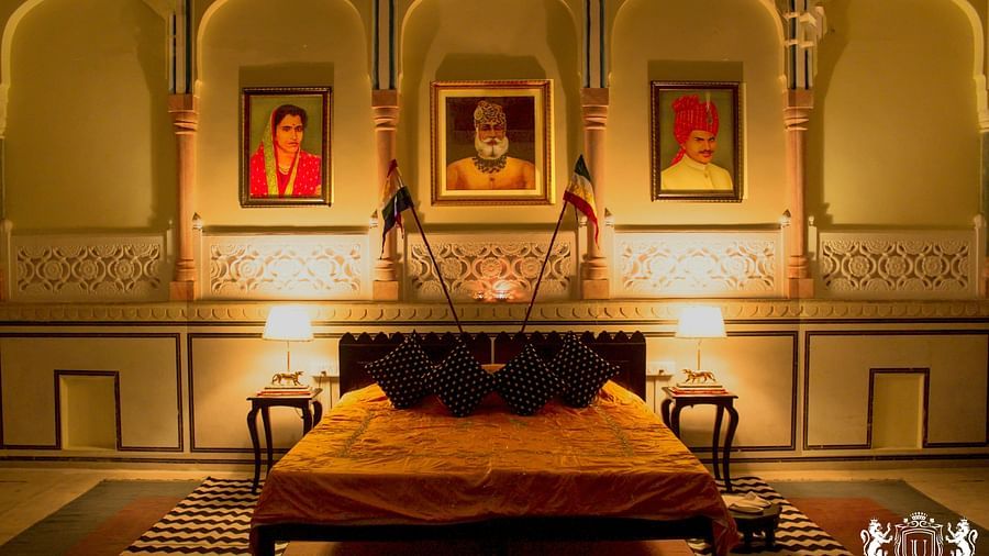 A bedroom at Umaid Vilas Jaipur with a low bed, framed portraits, and arched alcoves in the walls.
