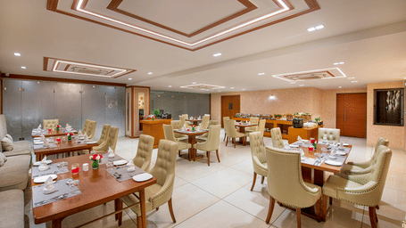 A hotel dining area with tables and chairs, prepared for breakfast or other meals - SK Lords Inn Ahmedabad