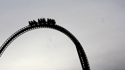 A far out view of a roller coaster with the silhouette of the people and the cars in view - Amusement Parks in Doha