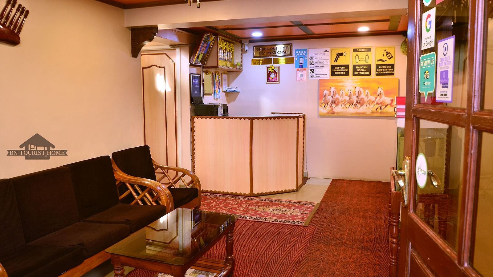 The reception desk at BN Tourist Home, Ooty, decorated with colourful posters and framed artwork - BN Tourist Home, Ooty