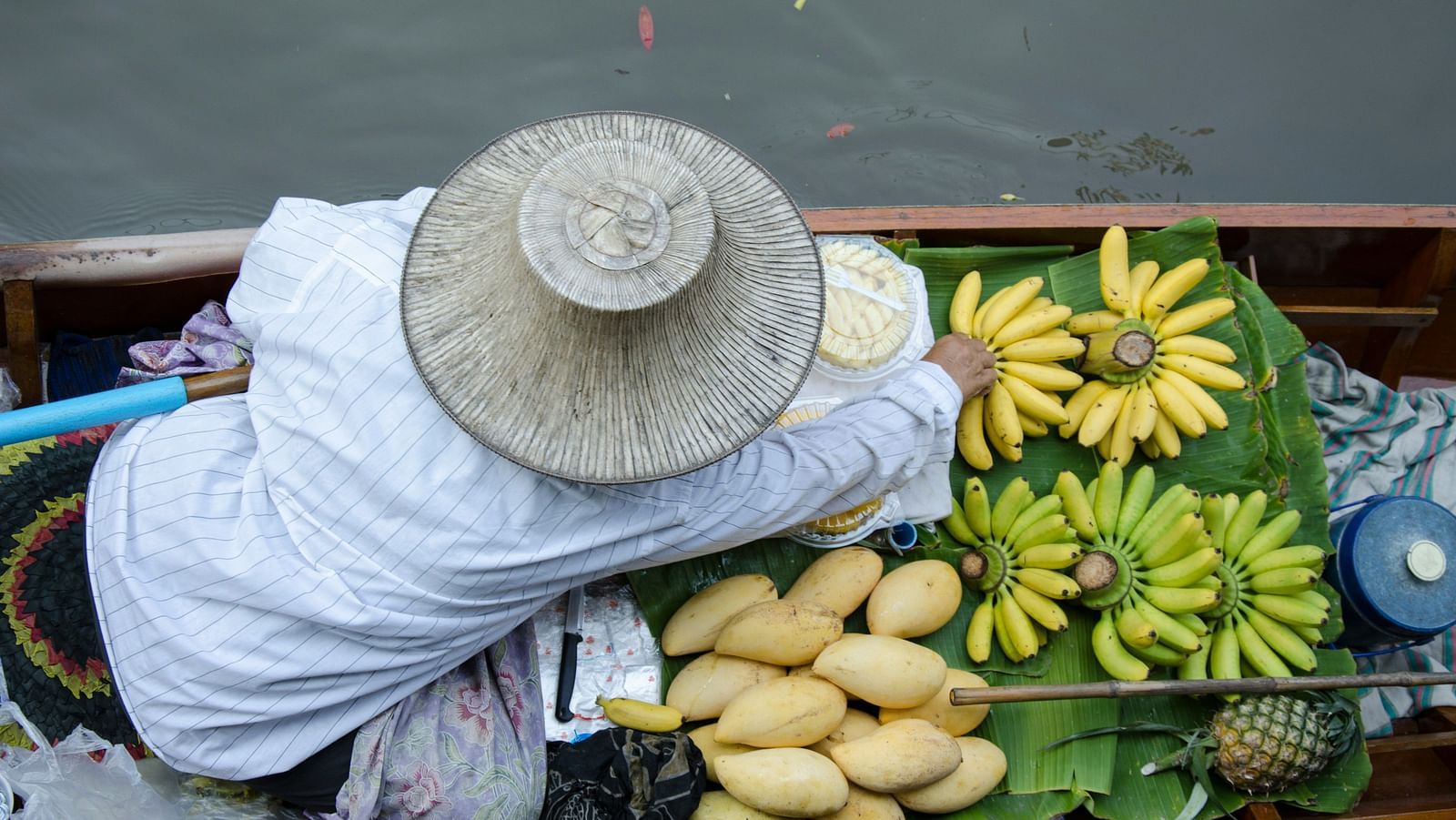 a person keeping bananas and other fruits before a sale in a floating market.