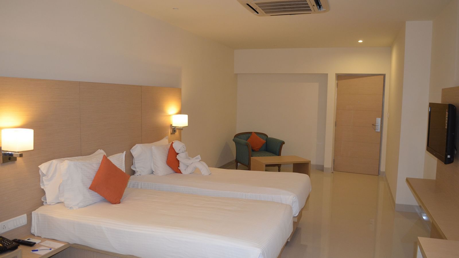 An image of twin beds with a television at a room at Regency Tiruttani by GRT Hotels. 