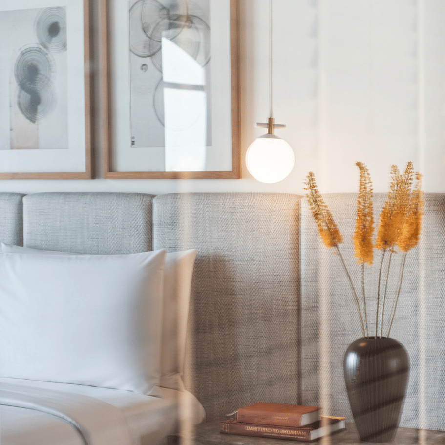Bedroom corner with bed, wall art, and bedside lamp at The Raintree, St. Mary’s Road.