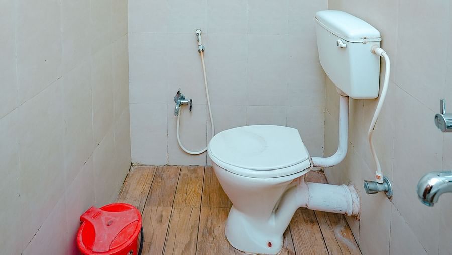 An image of a bathroom featuring a commode, a geyser and shower head, a dustbin, and a bucket - Rangamati Garden Resort
