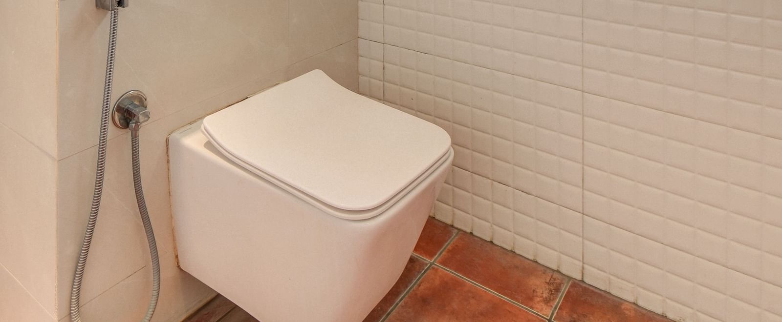 A spacious washroom with a western toilet and a window with frosted glass at Harigovinda's JNStay