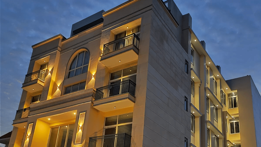 Low-angle exterior view of a multi-storey boutique hotel building lit up against a dusk sky.