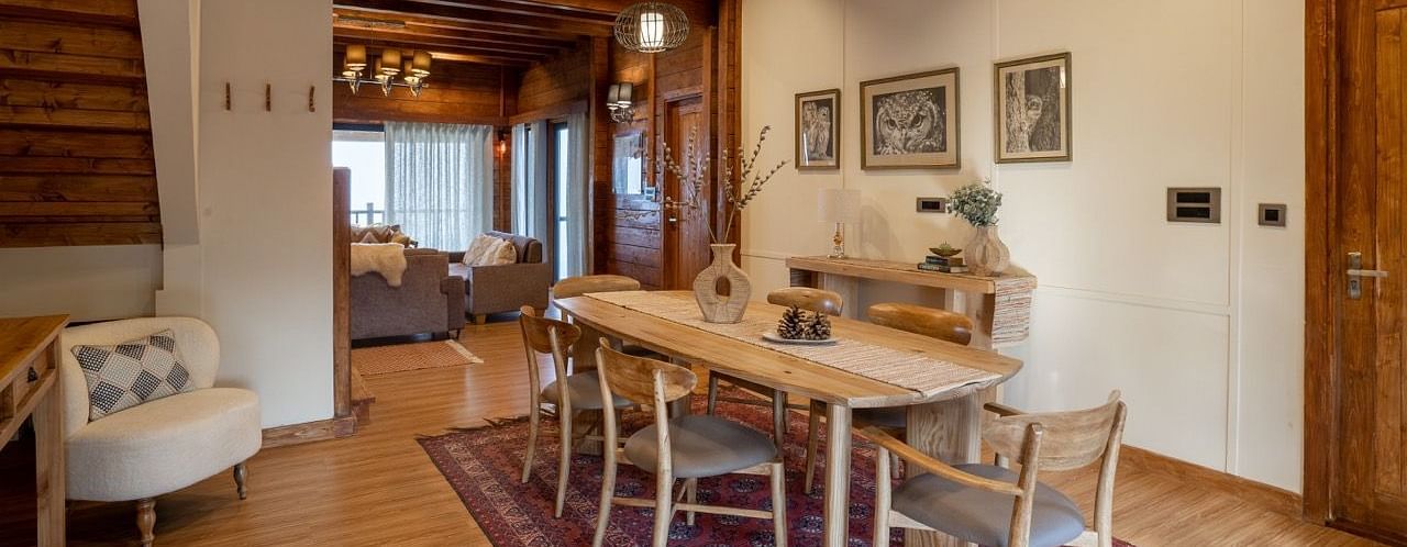 An image of dining space with table and chairs and stairs leading to the attic - Avalon Cottages, Kanatal
