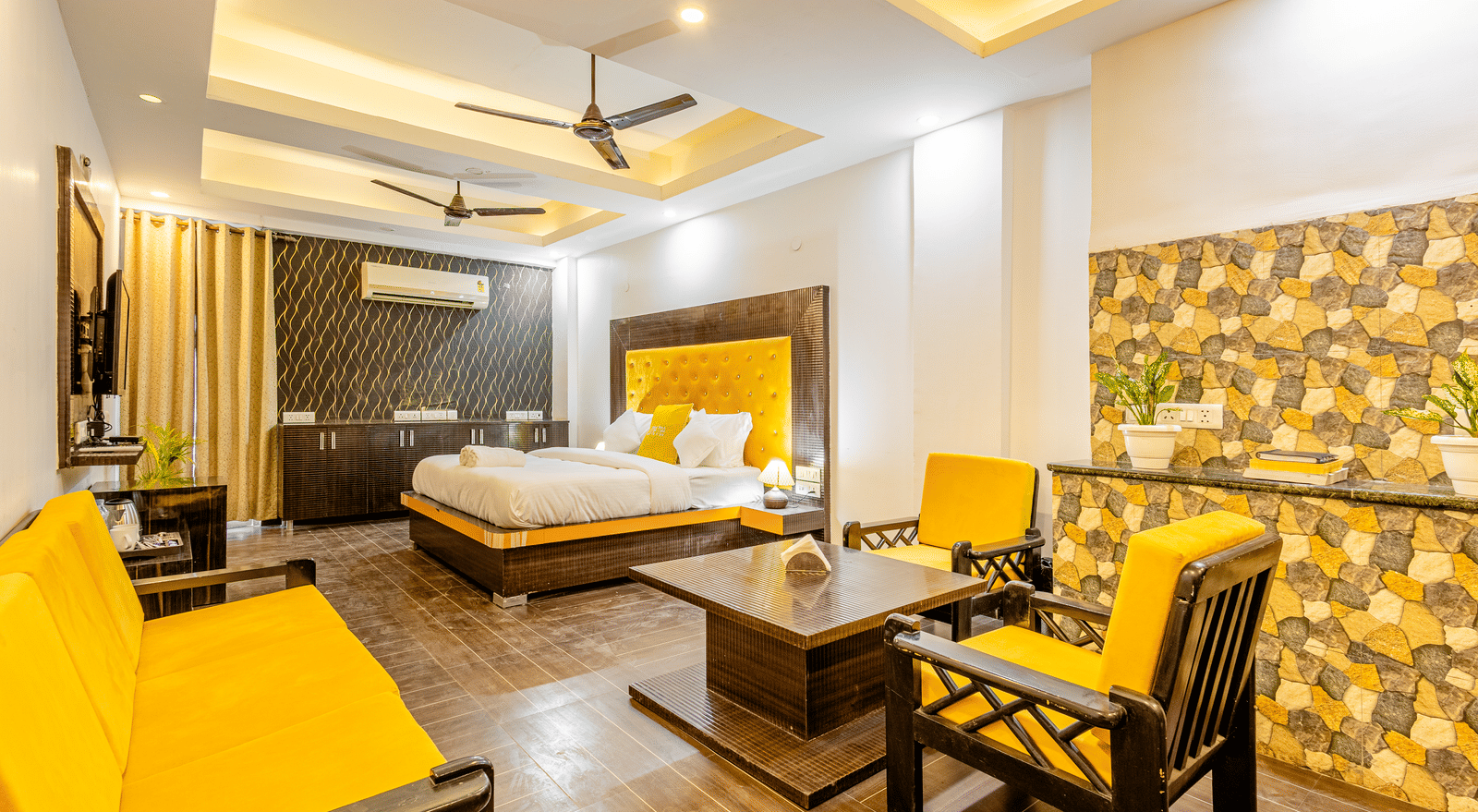 An image of a suite with king size bed, a flat TV screen, a seating area with chairs and a table, and a sofa - Lime Tree Hotels and Banquet Hall Huda Metro, Gurgaon