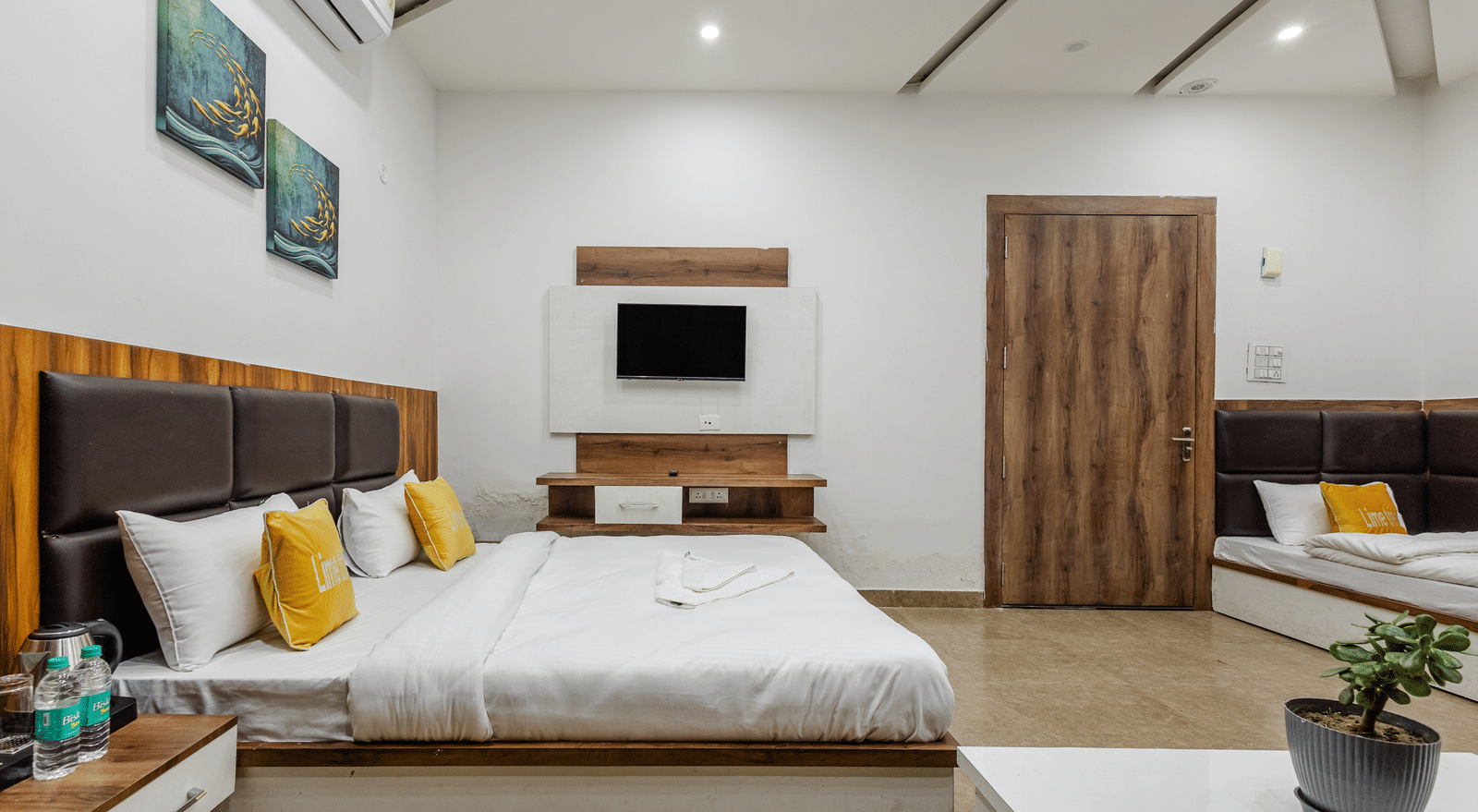 A bedroom with a modern ceiling, yellow cushions, and a TV unit facing the bed - Lime Tree Hotels & Banquet, Vrindavan