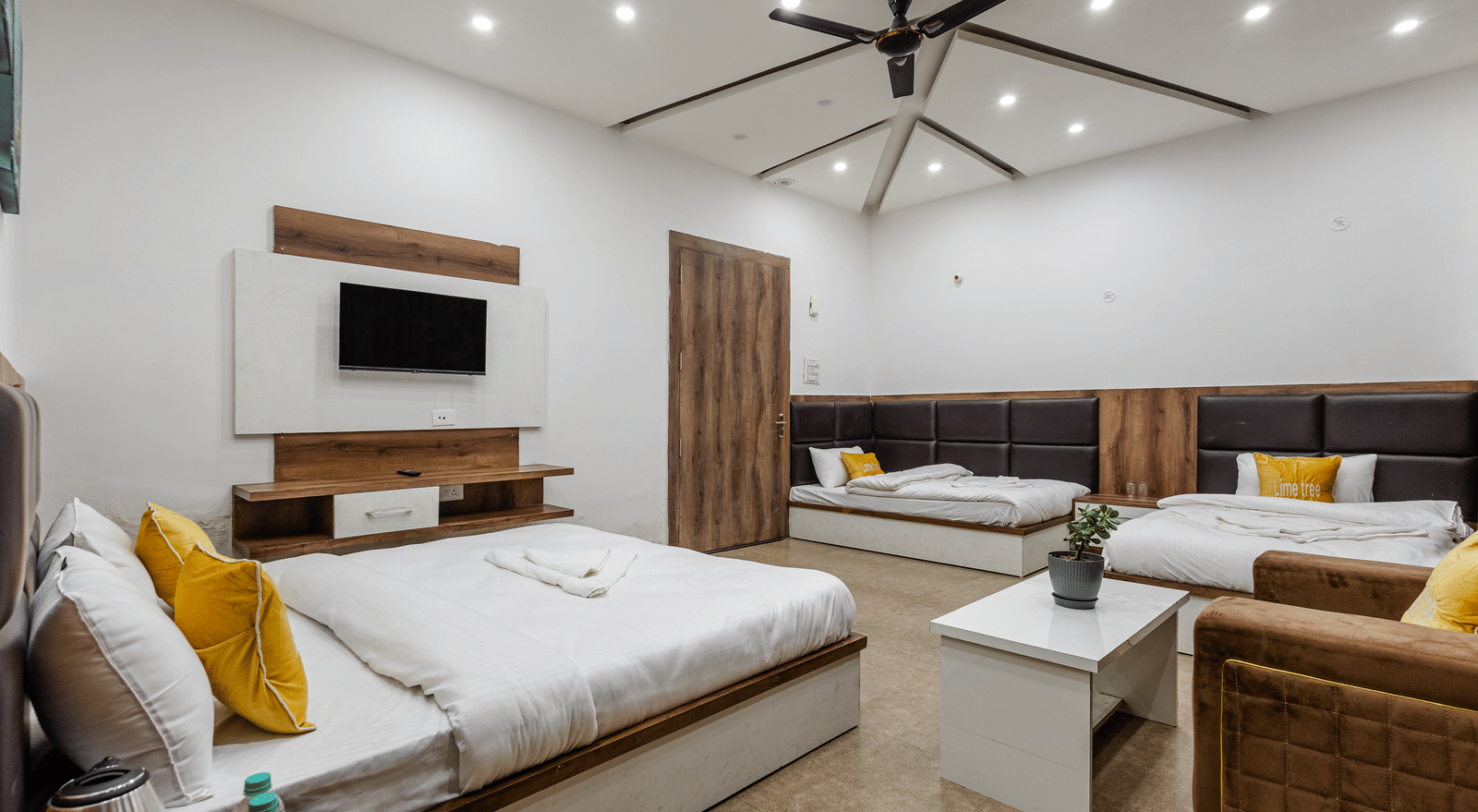 A bedroom featuring wooden furniture, ceiling fan, and a TV unit - Lime Tree Hotels & Banquet, Vrindavan